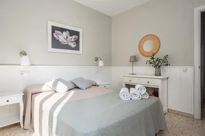 a white bedroom with a bed with shoes on it at Arenas 65 in Chiclana de la Frontera