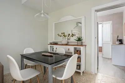 a dining room with a black table and white chairs at Arenas 65 in Chiclana de la Frontera