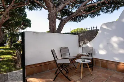 two chairs and a table on a patio with a tree at Arenas 65 in Chiclana de la Frontera