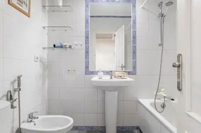 a white bathroom with a toilet and a sink at Complejo Atlantico in Chiclana de la Frontera