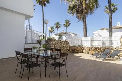 a white house with a courtyard with a stone wall at Complejo Atlantico in Chiclana de la Frontera