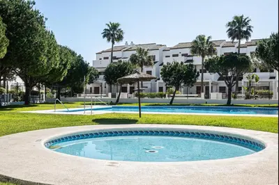 a swimming pool in front of a large building at carrajolilla 7B 13 in Chiclana de la Frontera