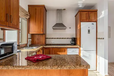 a kitchen with wooden cabinets and a white refrigerator at carrajolilla 7B 13 in Chiclana de la Frontera