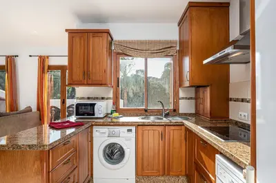 a kitchen with wooden cabinets and a washer and dryer at carrajolilla 7B 13 in Chiclana de la Frontera