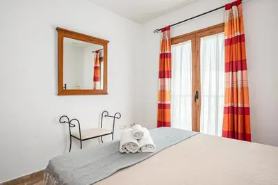 a bedroom with a bed and a mirror and a chair at carrajolilla 7B 13 in Chiclana de la Frontera