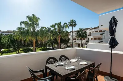 a table and chairs on a balcony with palm trees at carrajolilla 7B 13 in Chiclana de la Frontera