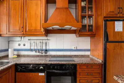 a kitchen with wooden cabinets and a black dishwasher at Laja Bermeja in Chiclana de la Frontera