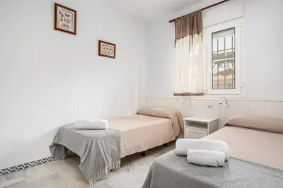 a room with two beds and a window at Laja Bermeja in Chiclana de la Frontera