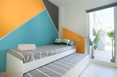 a bedroom with a bed with an orange and blue wall at Casa Nao Santiago - Sanlúcar de Barrameda - Centro Playa in Sanlúcar de Barrameda