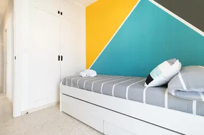 a bedroom with a bed with a blue and yellow wall at Casa Nao Santiago - Sanlúcar de Barrameda - Centro Playa in Sanlúcar de Barrameda