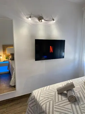a bedroom with a tv on the wall and a bed at Apartamento Las Sirenas in Chipiona