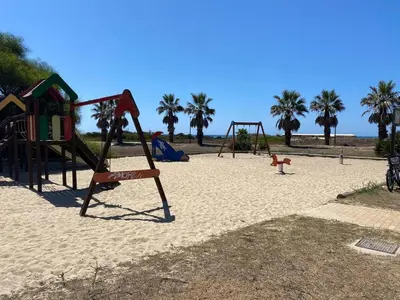 an empty playground on the beach with palm trees at Costa ballena en primera linea in Costa Ballena