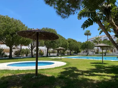 a pool with umbrellas in the grass next to at BARROSA CON ENCANTO, AC - WIFI - PARKING, Parejas y familias in Novo Sancti Petri