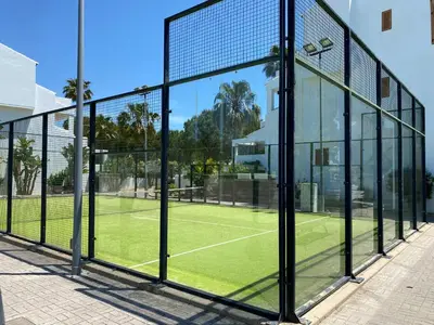 a tennis court with glass windows and a tennis court at BARROSA CON ENCANTO, AC - WIFI - PARKING, Parejas y familias in Novo Sancti Petri