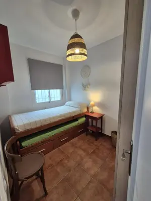 a room with a bed and a chair and a lamp at El Patio Grande in Sanlúcar de Barrameda