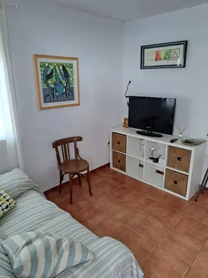 a living room with a television and a chair at El Patio Grande in Sanlúcar de Barrameda