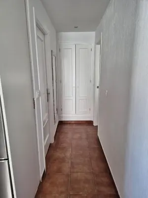 an empty hallway with white walls and a tile floor at El Patio Grande in Sanlúcar de Barrameda