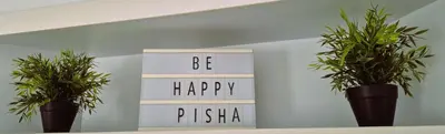 a sign that says be happy and two potted plants at Tacita de Plata by Gades Gestion in Cádiz
