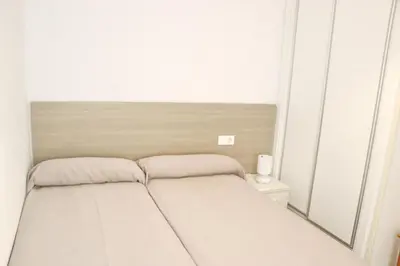 a small bedroom with a bed and a mirror at Apartamento Canario I in Conil de la Frontera