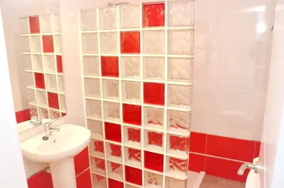 a bathroom with a sink and a shower with glass block walls at Apartamento Canario I in Conil de la Frontera