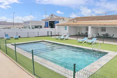 a swimming pool with chairs and a fence at Apartamento Canario I in Conil de la Frontera
