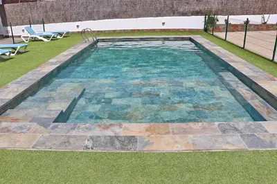 a swimming pool in a yard with a grass field at Apartamento Canario I in Conil de la Frontera