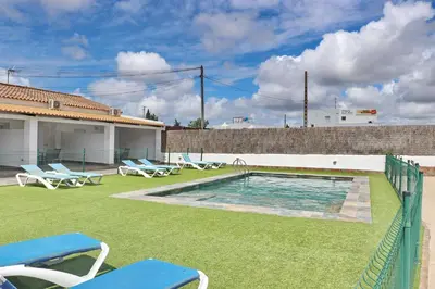 a backyard with a swimming pool with chairs and a fence at Apartamento Canario I in Conil de la Frontera