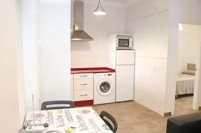 a kitchen with a washing machine and a table with chairs at Apartamento Canario I in Conil de la Frontera