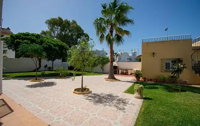 a courtyard with palm trees and a building at Chalet junto a la playa de La Barrosa in Novo Sancti Petri