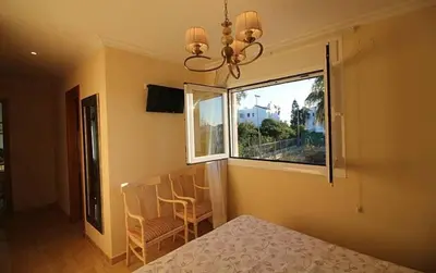 a bedroom with a bed and chairs and a window at Chalet junto a la playa de La Barrosa in Novo Sancti Petri