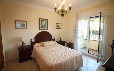a bedroom with a bed and a chandelier at Chalet junto a la playa de La Barrosa in Novo Sancti Petri