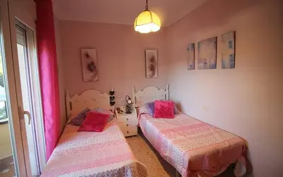 two beds in a room with pink and pink sheets at Chalet junto a la playa de La Barrosa in Novo Sancti Petri