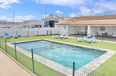 a swimming pool with chairs and a fence at Apartamento Canario II in Conil de la Frontera