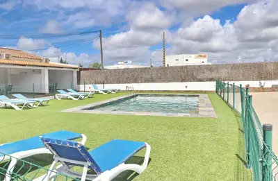 a pool with lawn chairs and a fence at Apartamento Canario II in Conil de la Frontera