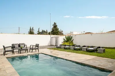 a backyard with a swimming pool with chairs and tables at Chiclana Dreamhouse in Chiclana de la Frontera