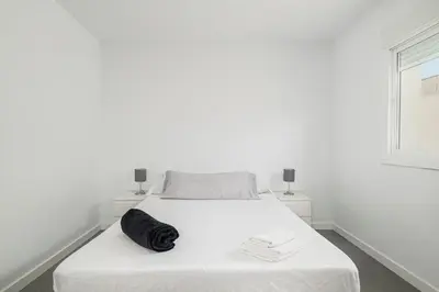 a white bedroom with a white bed with a black blanket at Chiclana Dreamhouse in Chiclana de la Frontera