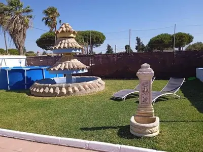 a fountain in the grass with two chairs and a table at La fuente in Novo Sancti Petri