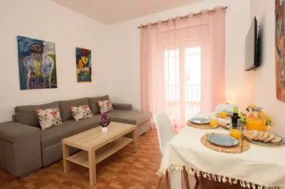 a living room with a table and a television on the wall at Descubre El Puerto de Santa María desde el corazón de su casco histórico in El Puerto de Santa María