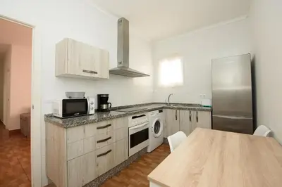a kitchen with a table and a refrigerator at Descubre El Puerto de Santa María desde el corazón de su casco histórico in El Puerto de Santa María