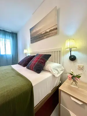 a bedroom with a bed and a table with a lamp at GATU Magavi Playa parking piscinas terraza 