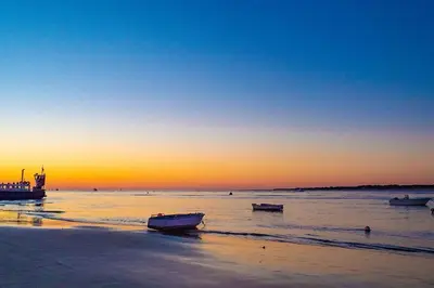 a beach with boats in the water at sunset at Apto G2 SANLUCAR DE BARRAMEDA in Sanlúcar de Barrameda