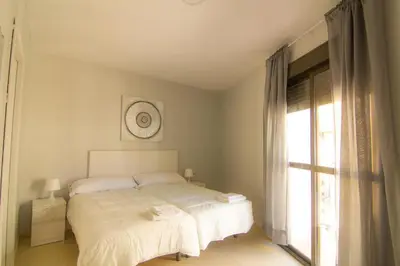 a white bedroom with a bed and a window at Apartamentos Jerez centro in Jerez de la Frontera