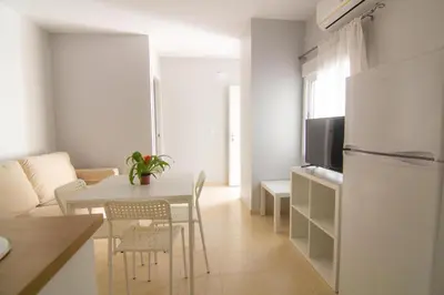 a kitchen and living room with a table and a refrigerator at Apartamentos Jerez centro in Jerez de la Frontera