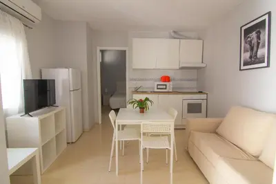 a small kitchen and living room with a table and a couch at Apartamentos Jerez centro in Jerez de la Frontera