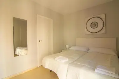 a bedroom with a white bed and a mirror at Apartamentos Jerez centro in Jerez de la Frontera