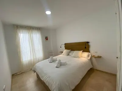 a bedroom with a bed with white sheets and a window at Apartamentos Tartaneros 4 in Sanlúcar de Barrameda
