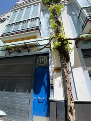 a building with a blue door and a tree at Apartamentos Tartaneros 4 in Sanlúcar de Barrameda