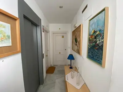 a hallway with a table and paintings on the wall at Apartamentos Tartaneros 4 in Sanlúcar de Barrameda