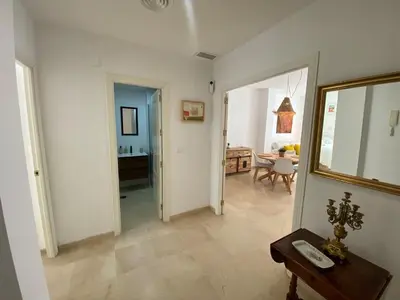 a living room with a hallway with a table and a mirror at Apartamentos Tartaneros 4 in Sanlúcar de Barrameda