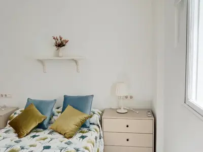 a bedroom with a bed with blue and yellow pillows at Apartamento Fuente de Los Naranjos in Jerez de la Frontera